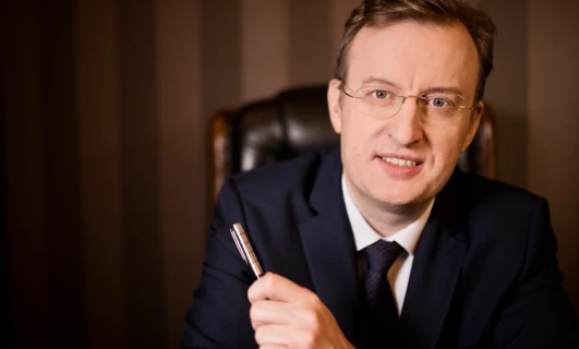 Mężczyzna w eleganckim ubraniu w okularach na czole, palec na brodzie, prezentujący opiekę nad wzrokiem.