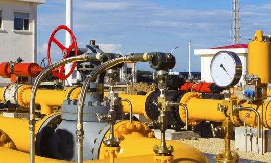 Stalowa rura łączy maszynę z stacją pompowania w fabryce przemysłowej. Inżynieria spotyka się z przemysłem w tym złożonym systemie cylindrów i zaworów.